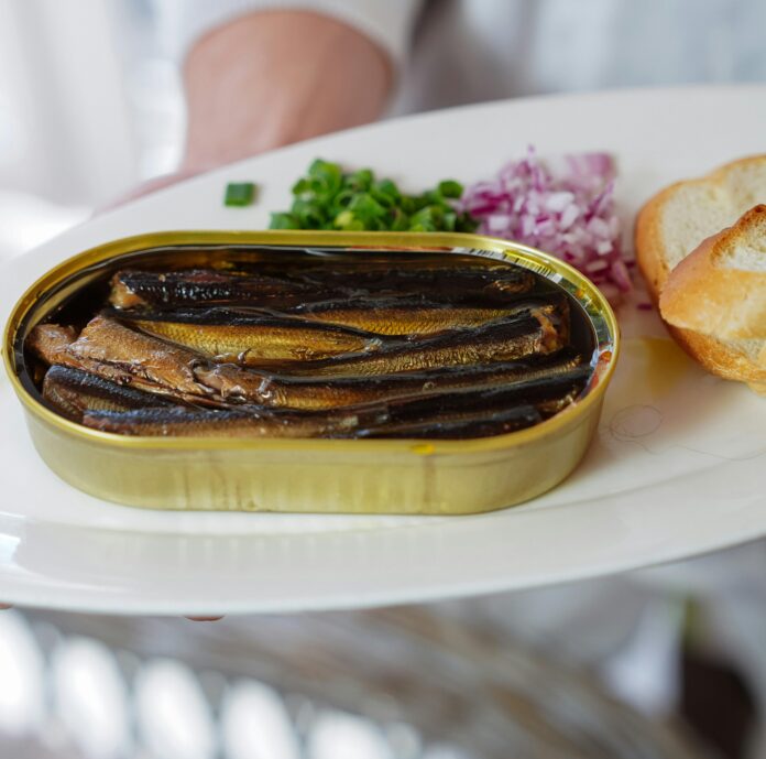 Person Holding a Plate with Canned Sardine Fish